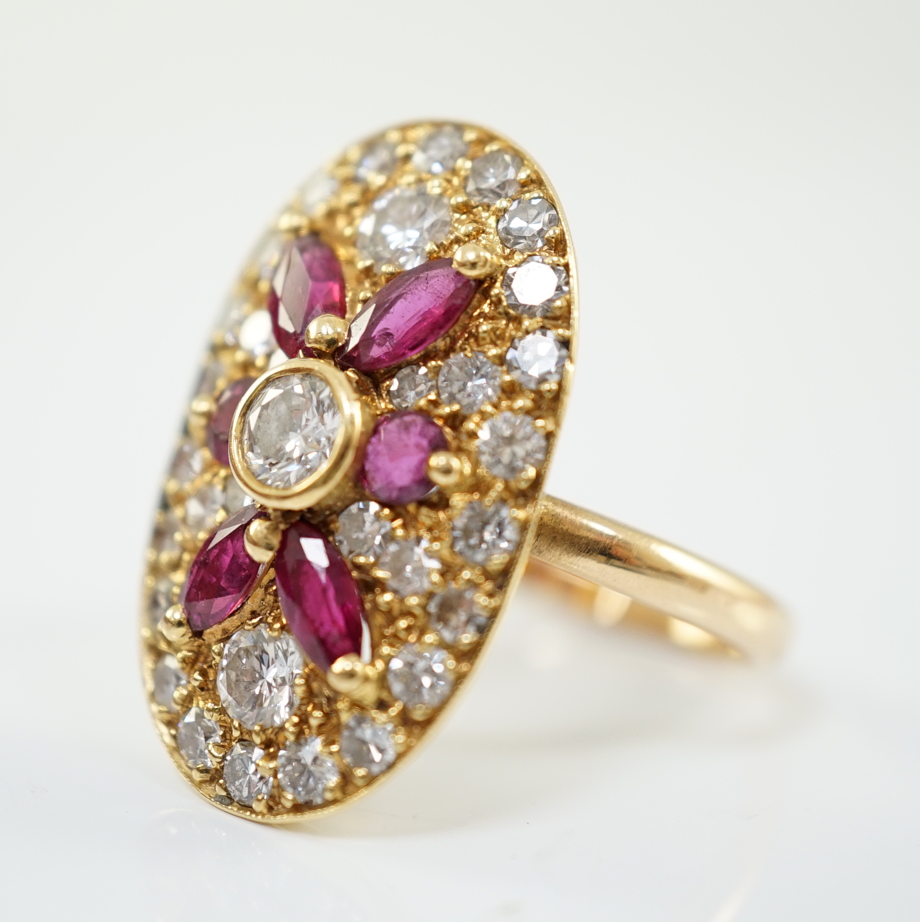 A modern gold, ruby and diamond set oval cluster ring